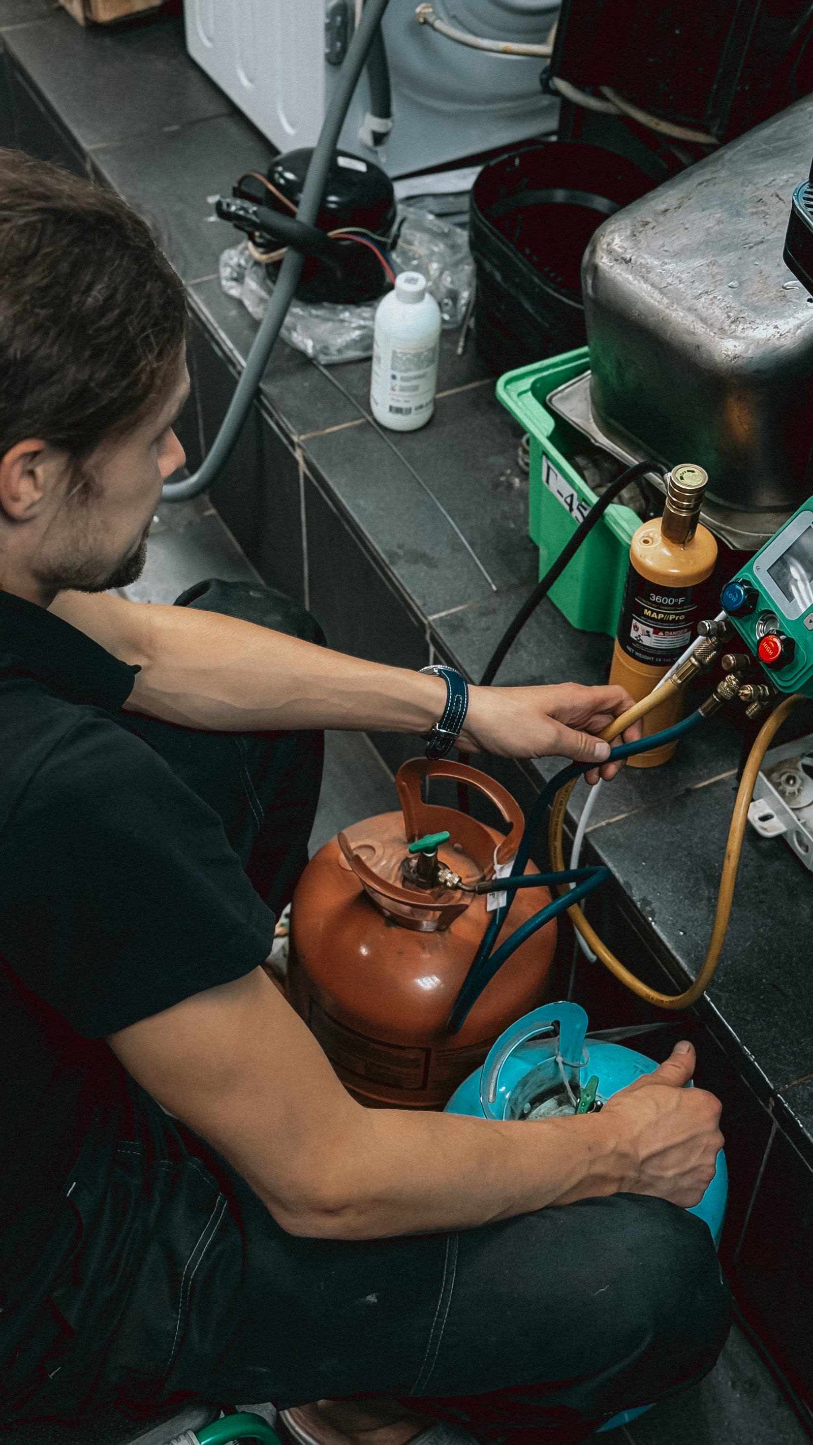 Refrigeration technician charging a system from refrigerant cylinders with a gauge manifold, walk-in cooler repair in Ridgefield, WA